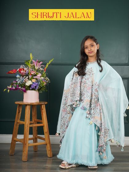 This little girl is wearing my sky blue cape set, a truly magical outfit. The flowing cape with floral prints and tassels makes it a standout piece for any special event.