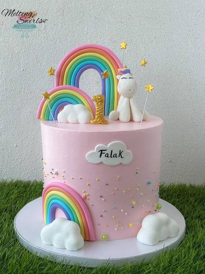 A tall and elegant unicorn cake for a first birthday celebration. This design features multiple rainbows, fluffy clouds, and a sweet fondant unicorn, creating a truly magical first cake.