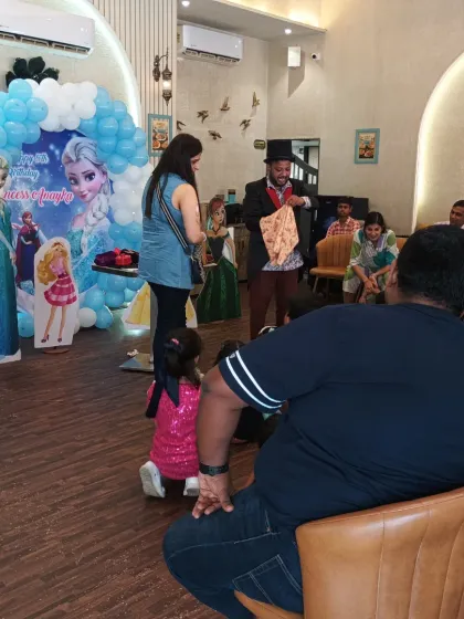 The magician performing his show for the entire audience, both kids and adults, at a Frozen-themed party.