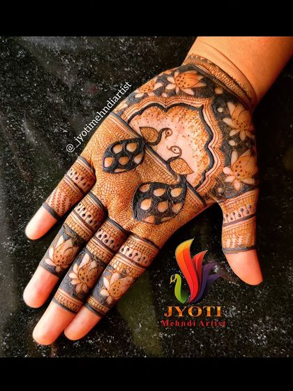 A lovely Indian mehndi design for the palm. This pattern features two small peacocks under an arch, surrounded by lotus and leaf motifs.