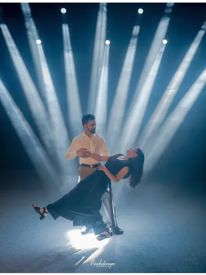 A couple strikes a dramatic dance pose, enveloped in ethereal beams of light in a studio setting. This demonstrates my technical skill in using creative lighting to craft glamorous and high-impact pre-wedding portraits.