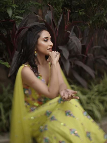A side profile of the mehendi look, showing the playful hairstyle and the radiant makeup that enhances her natural beauty.