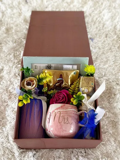A beautifully arranged birthday gift box for a special someone. This hamper includes a "Mrs." mug, a wrapped candle, and a selection of chocolates and other treats, making for a classic and romantic birthday gesture.