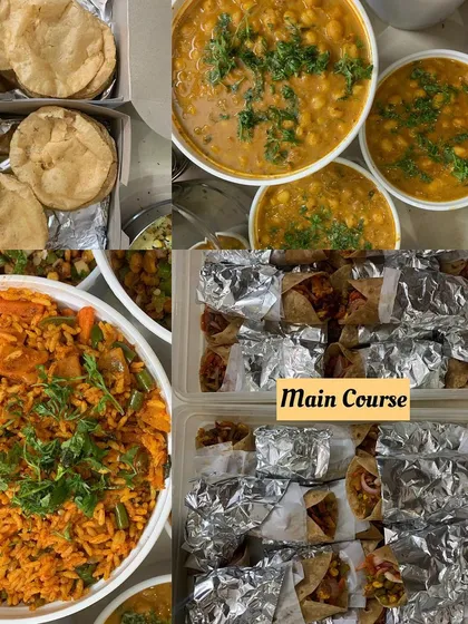A main course spread for a party. This includes Tawa Pulao, Chole, Puris, and freshly made veggie frankies, all wrapped and ready to be served.