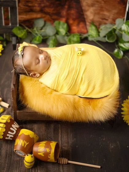 Our little honey bee. This newborn is peacefully sleeping in a "House of Honey Bee" setup, surrounded by sunflowers, honey pots, and tiny bee props.