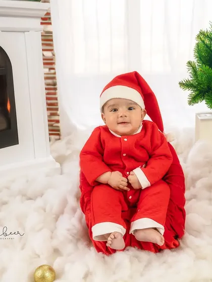 Our little Santa is all smiles in this festive Christmas setup, complete with a cozy fireplace and a golden reindeer.