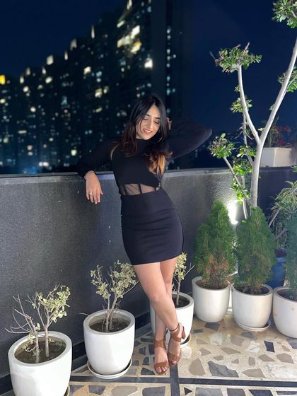 A sleek black dress with a mesh panel on a rooftop. This is a classic "little black dress" with a modern, edgy twist.