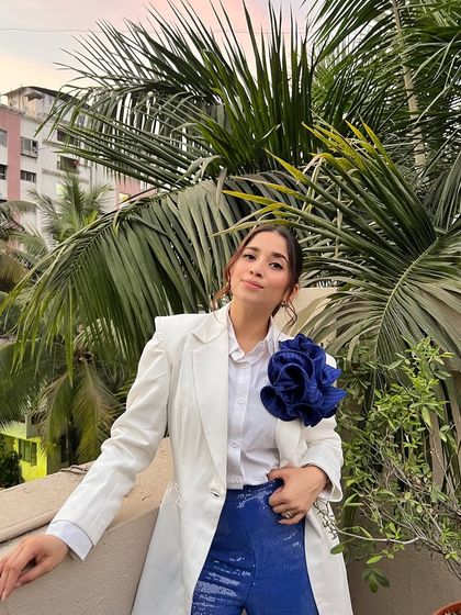 Taking my fit checks seriously. This look features a classic white blazer paired with bold, sequined blue trousers and a statement floral brooch.