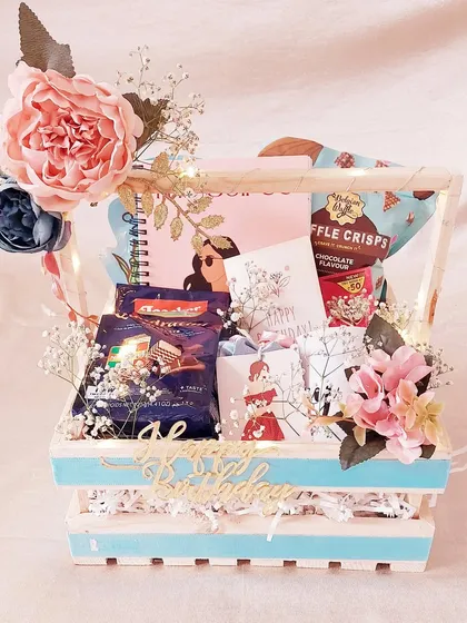 A personalized gift basket for a birthday girl. This light-up pinewood crate is filled with her favorite snacks and a custom notebook, making it a truly special gift.