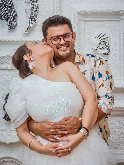 A sweet kiss on the cheek that radiates happiness. This candid moment from an engagement party captures the couple's affection in a relaxed and natural way.