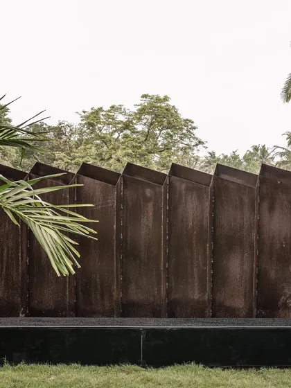 A close-up of the custom-patterned metal boundary wall. The weathered finish and geometric design provide a textural contrast to the surrounding greenery, demonstrating our attention to detail in every element of the project.