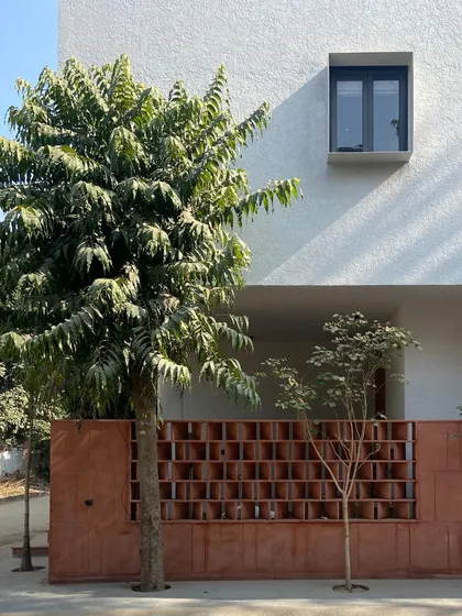 A street-level view of the Jaipur House, showcasing the contrast between the earthy red sandstone and the crisp white upper volume. The design makes a subtle but confident statement in its neighborhood.