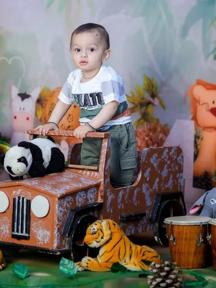 A toddler stands up in his safari jeep, ready to spot some wildlife. This pose is great for capturing the energy of a one-year-old.