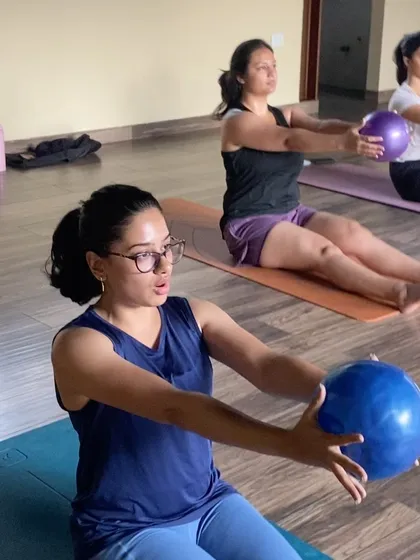 A close-up of me demonstrating an exercise with a small stability ball. Using props like these adds variety and intensity to our mat workouts, helping to target specific muscle groups more effectively.