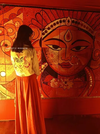 My art meets traditional art. Here I am in my hand-painted Durga jacket, standing before a magnificent Durga mural. It’s a beautiful moment of connection between my wearable art and larger-than-life festive decorations.