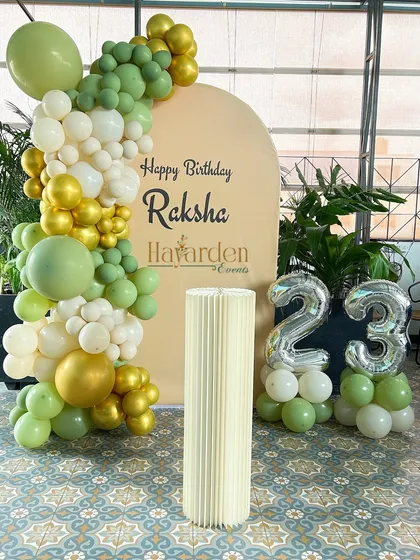 A fresh and modern 23rd birthday setup. The green, white, and gold balloon garland is paired with silver foil numbers for a stylish look.