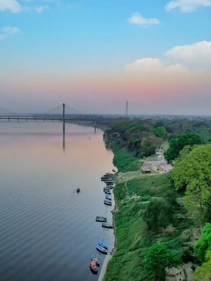 The calm waters of the Ganga river in Prayagraj, with the New Yamuna Bridge in the background. A serene view of my Sangam city.