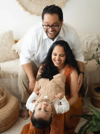 A family having fun, with the parents holding their baby upside down. This playful shot shows the joyful and energetic side of family life.