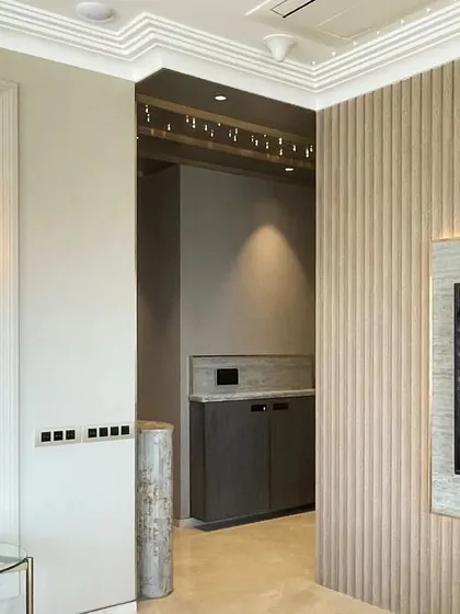 Texture and lighting are paramount in this Art Deco-inspired space. Fluted wall panels create a subtle rhythm, while a classic glass wall sconce provides warm, ambient light.