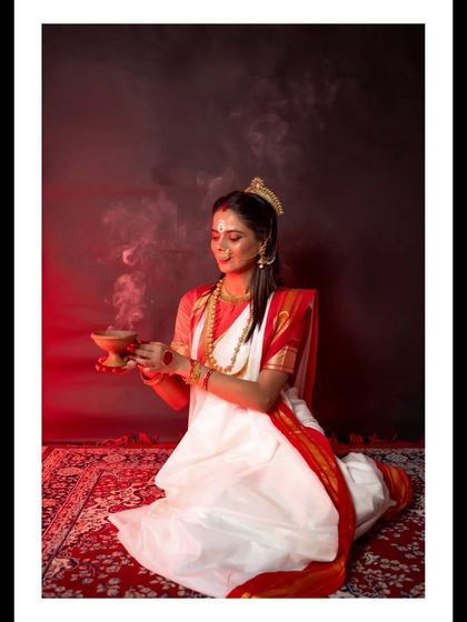 A woman performing a ritual with a 'dhunuchi' (incense burner) during a Durga Puja themed shoot. The smoke and dramatic red lighting create a divine and powerful atmosphere, celebrating Bengali culture.