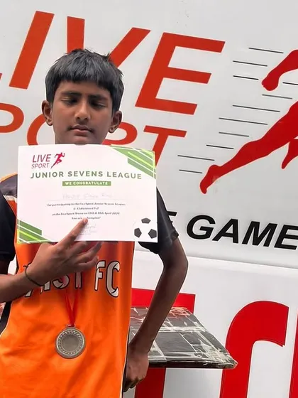 A young player proudly displays his certificate and medal after the Junior League finals.
