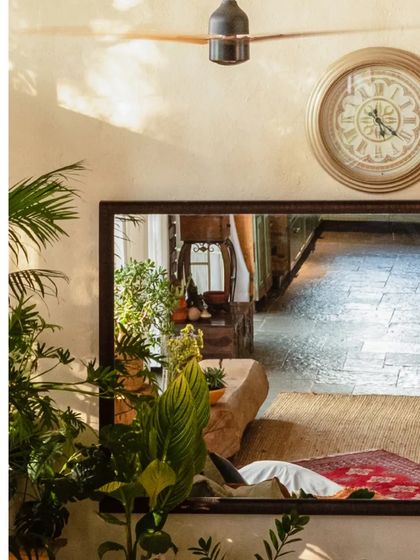 A large mirror reflects the living space, creating a sense of depth and showcasing the interplay of different rustic elements and textures.