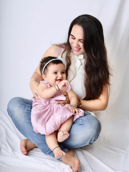 A relaxed and candid photo of a mother and her baby girl sharing a laugh on the studio floor.