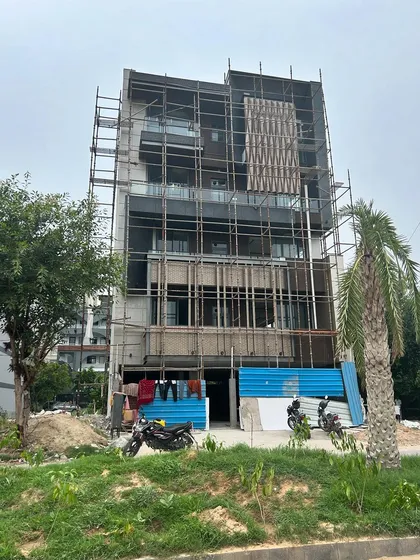 A builder floor project under construction, with scaffolding up for the facade work. The design incorporates stone cladding and decorative screens.