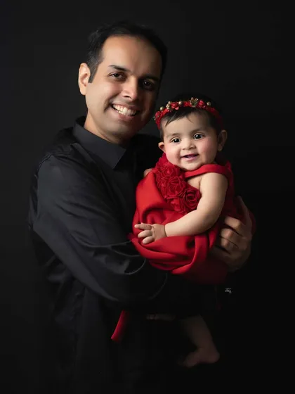 A proud father holds his daughter, who is beaming for the camera. This is a heartwarming father-daughter portrait that they will cherish for years to come.
