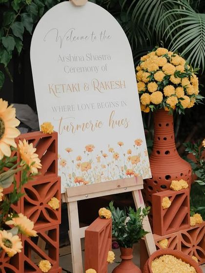 A closer look at the Haldi entrance decor. The custom welcome sign is surrounded by sunflowers and marigolds in terracotta vases, creating a rustic yet cheerful first impression.