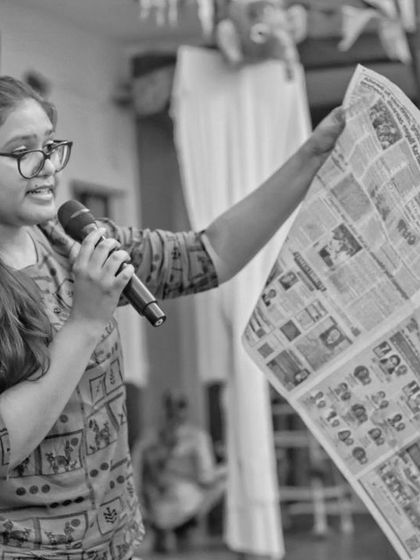 A black and white photo capturing a moment of instruction during a puppet class. We often incorporate simple props like a newspaper to spark new ideas for stories and characters.