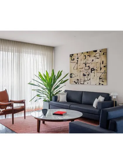 A view of the living room, featuring a deep blue sofa and a leather armchair. I select and design furniture to create a comfortable and sophisticated space for the whole family to gather.