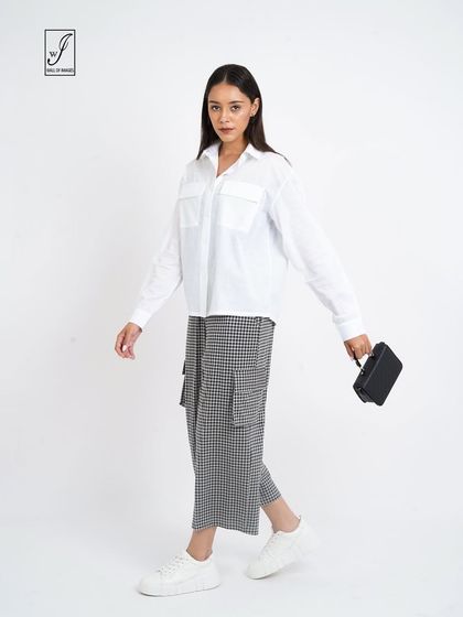 A walking pose in a white shirt and checkered pants, demonstrating how the clothes move and look in action.