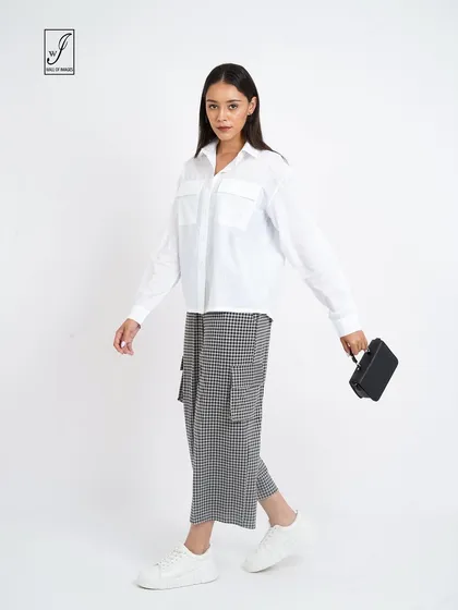 A walking pose in a white shirt and checkered pants, demonstrating how the clothes move and look in action.