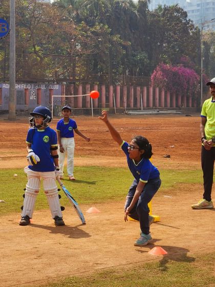 A young girl bowls to a batsman during a practice session on a mud pitch. This image demonstrates our inclusive approach, providing quality coaching and opportunities for both boys and girls to excel in cricket.