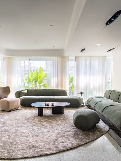Another perspective of the living area in Apartment 56, showing the sculptural furniture and the way the space flows around the custom-shaped rug. The design creates distinct zones within the open plan without using walls.