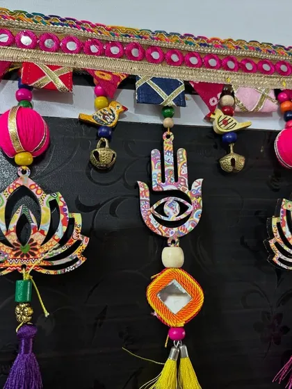 A close-up of the 'Shubh Toran', showing the detailed craftsmanship of the lotus and hamsa elements, along with the tiny birds and bells.
