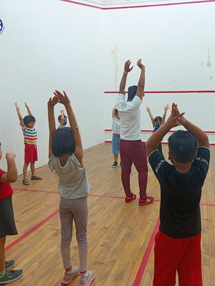 Young children participate in a stretching session in a squash court. We adapt our programs to the available spaces, ensuring a quality session every time.