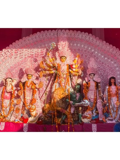 A Durga idol set against an intricate white backdrop, creating a stunning visual contrast during the daytime.