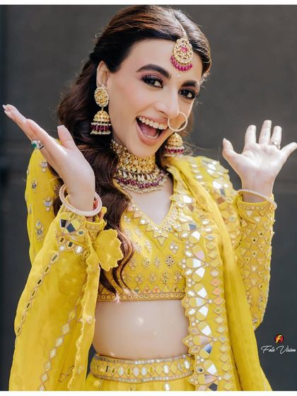 A bride's vibrant and expressive portrait during her Mehendi ceremony, her joy shining through in her bright yellow outfit.