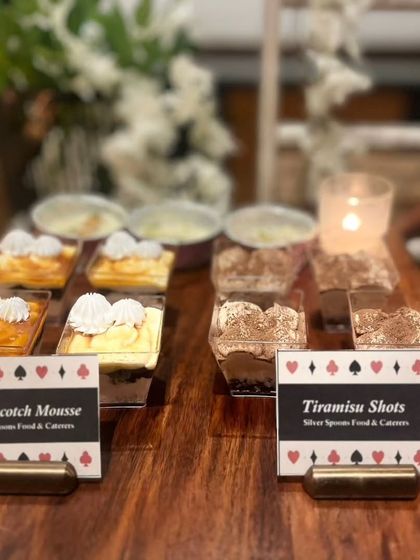 A dessert selection featuring individual portions of Butterscotch Mousse and Tiramisu Shots. The card-themed labels make them a perfect sweet ending for a Diwali cards party.