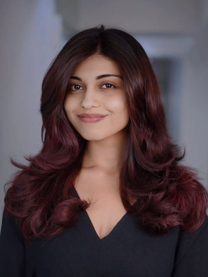 A smiling portrait of our client, clearly loving her new powerful red hair color and voluminous layered style.