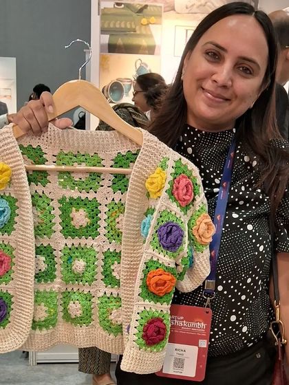 A visitor at Startup Mahakumbh holding our colorful granny square floral jacket. It's always wonderful to see the immediate connection people have with our wearable art.