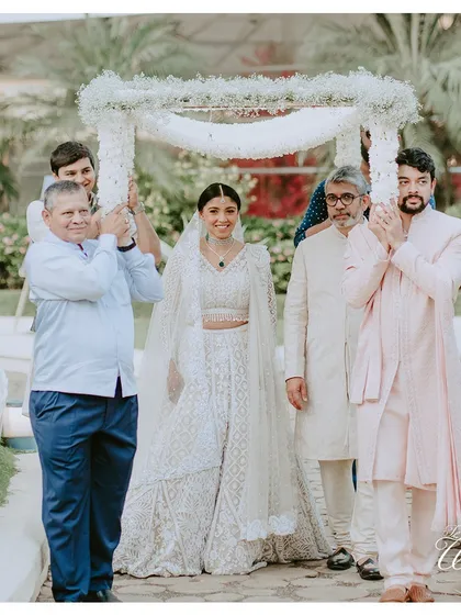 A full-length shot of the bride's graceful entry. The simplicity and elegance of the white floral chaadar perfectly complement her stunning ivory lehenga.