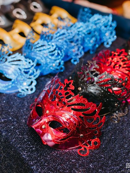 An array of ornate masquerade masks ready for guests. Providing thematic props is a simple way we ensure everyone gets into the spirit of the party.