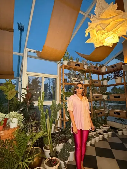 Posing in a greenhouse, this outfit feels both edgy and natural. The pop of pink from the leggings against the lush green background creates a beautiful visual contrast.