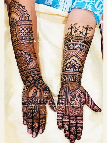 A beautiful engagement mehendi featuring love birds perched on trees. The hands have a mix of peacocks, mandalas, and delicate floral patterns.