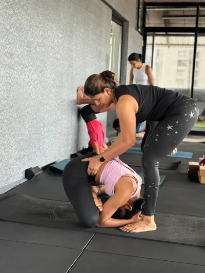 This is one of my favorite moments as a teacher. I'm helping a student find her balance in a headstand variation, and the pride I feel when she nails it is immense. Her win is my win.