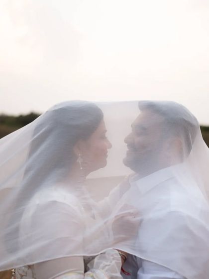 A silhouette of the couple under a flowing white veil, creating a dreamy and ethereal pre-wedding photograph.