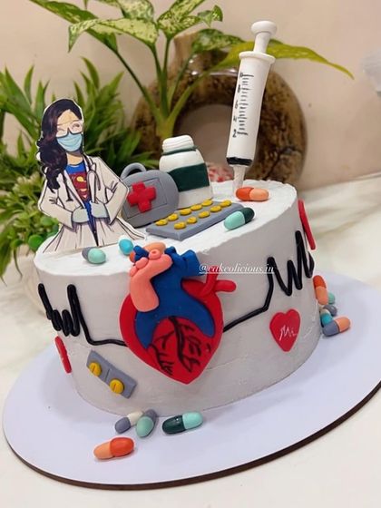 A customized cake for a doctor's birthday. This design is full of medical-themed fondant details, including a stethoscope, pills, a syringe, and an anatomical heart.